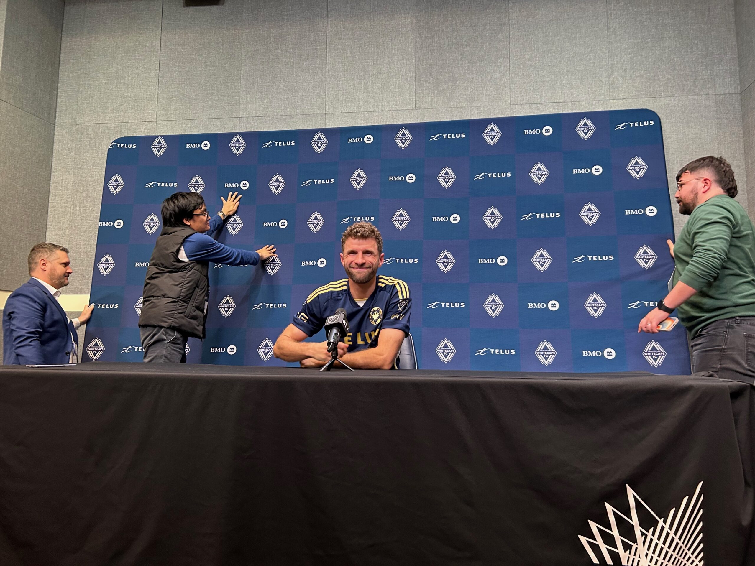 Media helping hold the backdrop that almost fell on an unconcerned Müller!