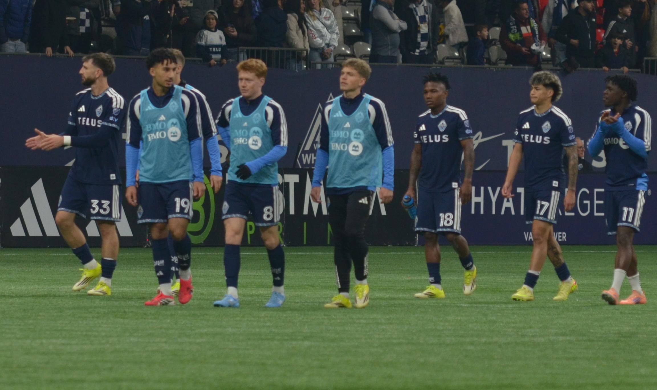 The reserves and some Whitecaps Players walking around the field together.